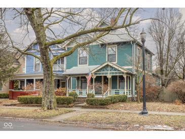 Charming two-story home with teal siding, inviting front porch, and a beautifully landscaped yard at 1468 Alabama St, Indianapolis, IN 46202