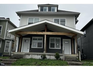 Traditional two-story duplex featuring a shared covered porch, concrete steps, and mixed siding at 2035 Carrollton Ave, Indianapolis, IN 46202