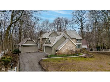 Stunning home features a unique roofline, stone accents, three car garage, and mature trees at 14519 Cherry Tree Rd, Carmel, IN 46033