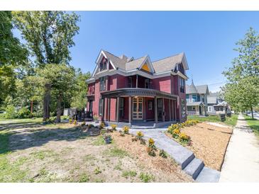 Beautiful red Victorian home with wrap-around porch and landscaped yard at 404 N State St, Greenfield, IN 46140