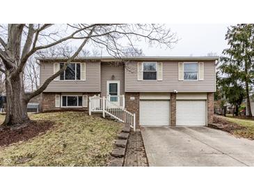 Charming split-level home featuring a two-car garage and a welcoming front entrance with stairs at 9229 Thrushwood Ln, Indianapolis, IN 46250