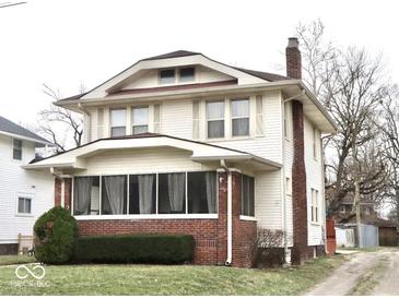 Charming two-story home featuring a brick foundation, enclosed front porch, and a well-maintained lawn at 917 E 34Th St, Indianapolis, IN 46205