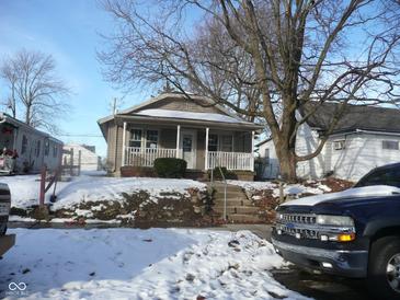 Tan house with porch, steps, and snow-covered yard at 1300 W 13Th St, Muncie, IN 47302