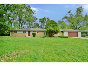 Ranch home with brick and siding, attached garage, and a spacious lawn with scattered trees at 4820 E 70Th St, Indianapolis, IN 46220