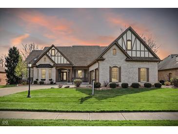 Beautiful, light brick home featuring a manicured lawn and Tudor-style architectural accents at 14565 Geist Ridge Dr, Fishers, IN 46040