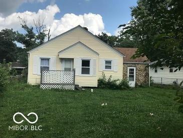 Ranch home with a yellow exterior, green lawn, and stone addition at 4025 N Kitley Ave, Indianapolis, IN 46226