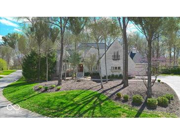 Charming white brick two-story home with manicured lawn and mature trees at 9399 Irishmans Run Ln, Zionsville, IN 46077