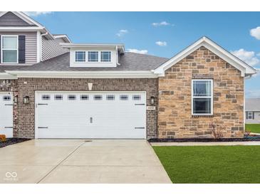 Two-car garage on a charming home exterior featuring brick and stone accents, plus manicured front lawn at 6433 Wasco Dr, Whitestown, IN 46075