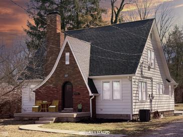 Charming home featuring a brick and siding exterior, complemented by a well-manicured lawn and cozy front porch seating area at 2029 W 60Th St, Indianapolis, IN 46228