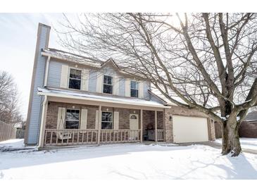 Charming two-story home featuring a cozy front porch and an attached garage, set in a snowy landscape at 12643 Feldspar Rd, Indianapolis, IN 46236