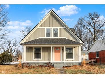 Charming craftsman style home with a gray exterior, pink door and front porch at 5704 E 16Th St, Indianapolis, IN 46218