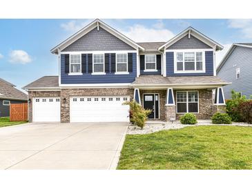 Charming two-story home with blue siding, brick accents, a well-manicured lawn and a three car garage at 1324 Trailside Dr, Greenwood, IN 46143