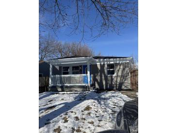 Gray brick ranch home with white porch and blue door, freshly landscaped yard at , Indianapolis, IN 46203