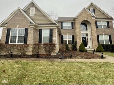 Charming two-story home featuring a brick and stone facade, black shutters, and manicured landscaping at 2504 Fawn Bluff Ct, Zionsville, IN 46077