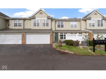 Two-story townhome featuring an attached garage, brick accents, and lush landscaping at 2231 Colfax Ln, Indianapolis, IN 46260