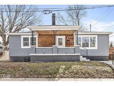 Charming home featuring gray siding, brick accents, and a cozy porch with wood paneling and wrought iron details at 2421 E 11Th St, Indianapolis, IN 46201