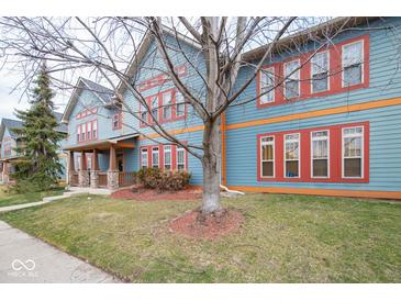 Townhome exterior with blue siding, red window frames, and a mature tree in the front yard at 1623 N College Ave # 2, Indianapolis, IN 46202