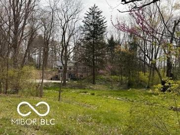 Secluded log home nestled amongst mature trees and lush greenery offers a private retreat at 7971 Conarroe Rd, Indianapolis, IN 46278