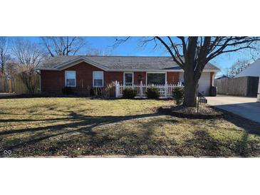 Charming brick home features a tidy front yard with a picket fence and mature landscaping at 831 Middle Dr, Whiteland, IN 46184