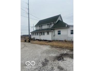White two-story home features a green roof, complemented by a gravel driveway and minimal landscaping at 756 S State Road 13, Lapel, IN 46051