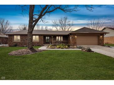 Charming brick ranch home featuring an attached garage, front porch, and a well-maintained lawn and mature tree at 8316 Hill Gail Dr, Indianapolis, IN 46217