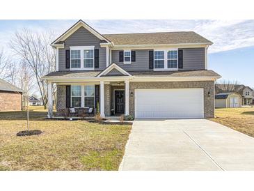 Charming two-story home features a brick and gray siding exterior, a welcoming front porch, and a two-car garage at 13115 N Departure W Blvd, Camby, IN 46113