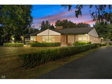 Charming brick home featuring a manicured front yard, mature trees, and an inviting entrance at 44 Kessler Blvd W Dr, Indianapolis, IN 46208
