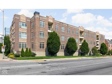 Brick apartment building featuring balconies, lush greenery, and well-maintained landscaping at 450 E Ohio St # Apt 118, Indianapolis, IN 46204