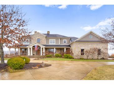 Stunning stone and siding home featuring a welcoming front porch and beautifully landscaped grounds at 5895 W 265 N, Columbus, IN 47201