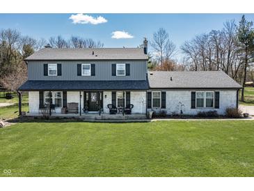 Charming two-story home featuring a front porch, gray siding, a white brick facade, and a lush green lawn at 7089 W 150 N, Greenfield, IN 46140