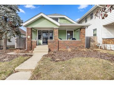 Charming green home with brick accents and inviting front porch with concrete steps at 1038 Cameron St, Indianapolis, IN 46203