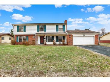 Inviting two-story home featuring a brick chimney, attached two-car garage, and manicured lawn at 5549 Hollister Dr, Indianapolis, IN 46224