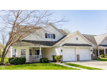 Inviting home featuring a two-car garage, front porch, manicured lawn, and charming architectural details at 3841 Constitution Dr, Carmel, IN 46032