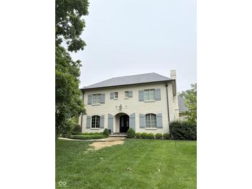 Charming two-story home featuring a light brick exterior, gray shutters, and a well-manicured lawn at 7525 N Pennsylvania St, Indianapolis, IN 46240