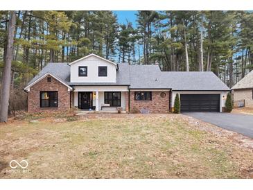Charming brick home with a white gabled roof and well-maintained landscaping surrounded by mature trees at 7643 Dean Rd, Indianapolis, IN 46240