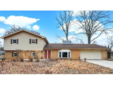 Charming split-level home with brick and siding exterior, attached garage, and solar panels on the roof at 1852 W 62Nd St, Indianapolis, IN 46260