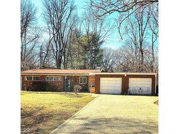 Charming ranch-style home featuring a brick facade and two-car garage, set on a spacious lot with mature trees at 5506 N Drexel Ave, Indianapolis, IN 46220