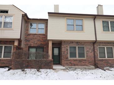 Charming townhouse featuring brick and neutral siding, complemented by snow-covered landscaping at 9523 Maple Way, Indianapolis, IN 46268