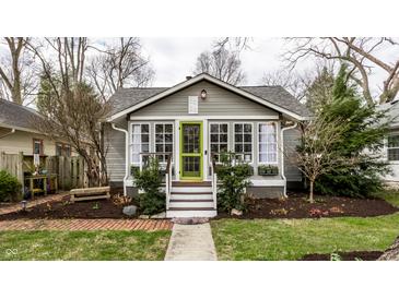 Charming gray craftsman home featuring a green door, gabled roof, and beautifully landscaped front yard at 5626 Winthrop Ave, Indianapolis, IN 46220