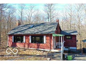 Charming red home with a brick chimney and gray roof nestled amongst mature trees at 9464 N State Rd 135, Morgantown, IN 46160