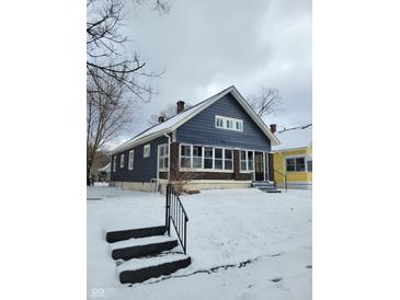Charming blue bungalow with brick foundation, multiple windows, and snow-covered yard at 2309 N Dearborn St, Indianapolis, IN 46218