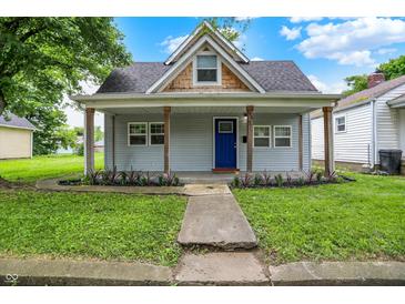 Charming home featuring a cozy front porch, blue door, and a well-maintained lawn and landscaped garden at 952 N Concord St, Indianapolis, IN 46222
