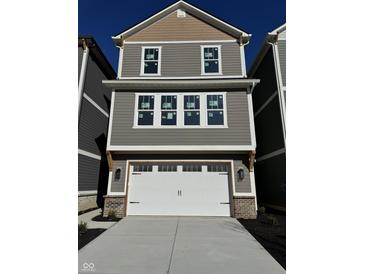 Two story home with a grey exterior, white garage door and trim, and black carriage style hardware at 15405 Mystic Rock Dr, Carmel, IN 46033