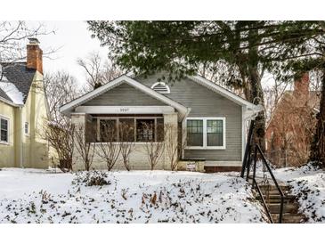 Charming two-story home featuring a covered porch and manicured front yard during winter at 5937 Broadway St, Indianapolis, IN 46220
