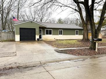 Charming single-story home featuring a black garage door, neat landscaping, and an inviting front entrance at 7824 Inverness Dr, Indianapolis, IN 46237