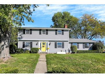 Charming two-story home with light gray siding, black shutters, and a bright yellow front door at 908 Whispering Trl, Greenfield, IN 46140