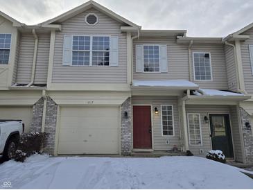 Two story townhome with a red front door and single car garage during the winter at 1017 Grovewood Dr, Beech Grove, IN 46107