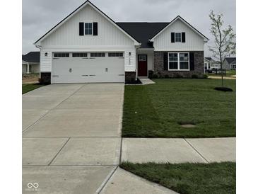 Charming two-story home featuring a two-car garage, a red door, and a well-manicured lawn at 1202 Brightwood Cir, Greenfield, IN 46140