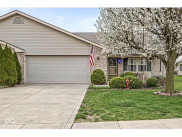 Charming single-story home features a well-manicured lawn, mature flowering tree, and a two-car attached garage at 4038 Oak Trail Dr, Indianapolis, IN 46237