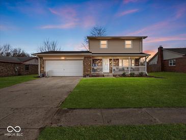 Charming two-story home with a covered front porch, attached garage, and well-manicured lawn at 5415 Honey Comb Ln, Indianapolis, IN 46221